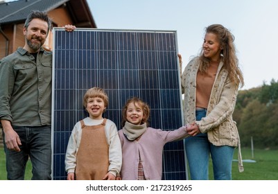 Happy family near their house with solar panels. Alternative energy source - Powered by Shutterstock