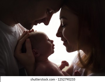 Happy family with newborn baby by the window