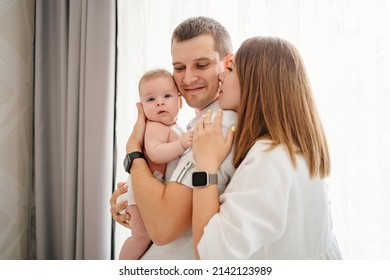a happy family with a newborn baby by the window. mom, dad and baby. psychological assistance to young parents. products and cosmetics for the whole family. foster family and adoption of children.
