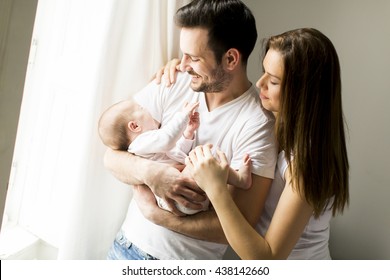 Happy Family With Newborn Baby By The Window