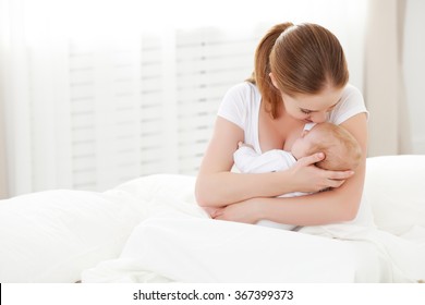 happy family newborn baby in an embrace his mother in a white bed - Powered by Shutterstock