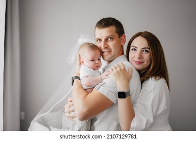 A Happy Family With A Newborn Baby At Home Near The Cot. Mom, Dad And Baby. Psychological Assistance To Parents. Products And Cosmetics For The Whole Family. Foster Family And Adoption Of Children.