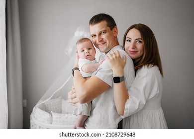 A Happy Family With A Newborn Baby At Home Near The Cot. Mom, Dad And Baby. Psychological Assistance To Parents. Products And Cosmetics For The Whole Family. Foster Family And Adoption Of Children.