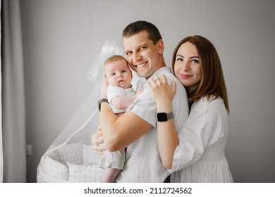 A Happy Family With A Newborn Baby At Home Near The Cot. Mom, Dad And Baby. Psychological Assistance To Parents. Products And Cosmetics For The Whole Family. Foster Family And Adoption Of Children.