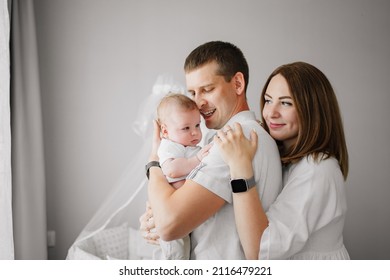 A Happy Family With A Newborn Baby At Home Near The Cot. Mom, Dad And Baby. Psychological Assistance To Parents. Products And Cosmetics For The Whole Family. Foster Family And Adoption Of Children.