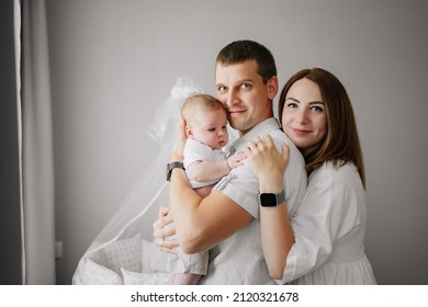 A Happy Family With A Newborn Baby At Home Near The Cot. Mom, Dad And Baby. Psychological Assistance To Parents. Products And Cosmetics For The Whole Family. Foster Family And Adoption Of Children.