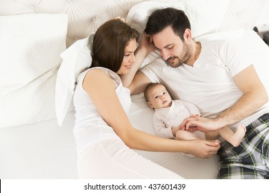 Happy Family With Newborn Baby On The Bed In The Room