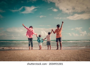 Happy family on the beach against blue sea and sky background at sunset. Holiday and summer travel concept - Shutterstock ID 2034931301