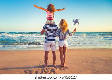 Happy Family On The Beach. People Having Fun On Summer Vacation. Father, Mother And Child Against Blue Sea And Sky Background. Holiday Travel Concept