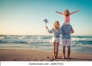 Happy family on the beach. People having fun on summer vacation. Father, mother and child against blue sea and sky background. Holiday travel concept