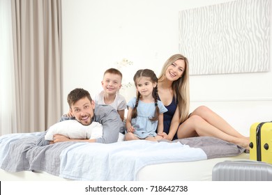 Happy family on bed in hotel room - Shutterstock ID 718642738