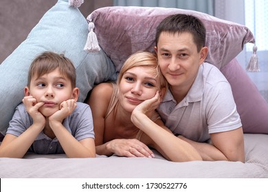 Happy Family On A Bed With Soft Pillows At Home