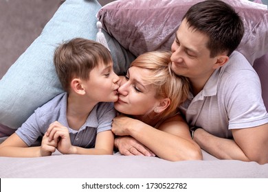 Happy Family On A Bed With Soft Pillows At Home