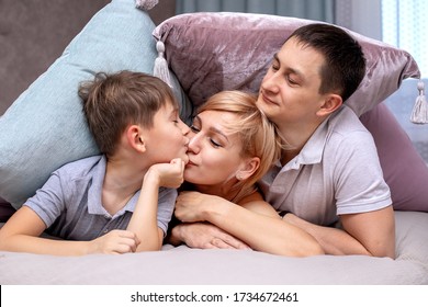 Happy Family On A Bed With Soft Pillows At Home