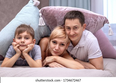 Happy Family On A Bed With Soft Pillows At Home