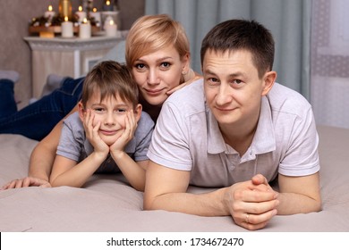 Happy Family On A Bed With Soft Pillows At Home