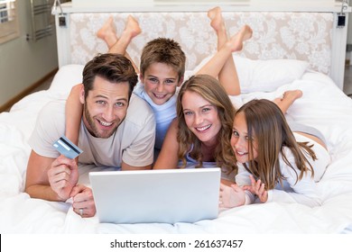 Happy family on the bed using laptop at home in bedroom - Powered by Shutterstock