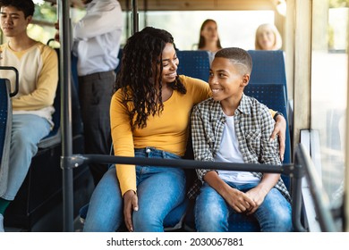 Happy Family On The Bus. Portrait of smiling young African American woman and boy sitting and going on a public transport, lady hugging son and looking at each other, enjoying ride or travel - Powered by Shutterstock