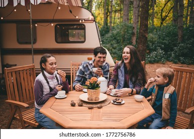 Happy family on a camping trip relaxing in the autumn forest. Camper trailer. Fall season outdoors trip