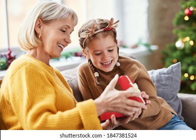 Happy family on Christmas morning. Affectionate grandmother and cheerful granddaughter open a holiday gift together at home
 - Powered by Shutterstock