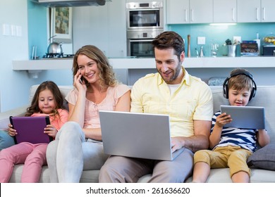 Happy Family On The Couch Together Using Devices At Home In The Living Room