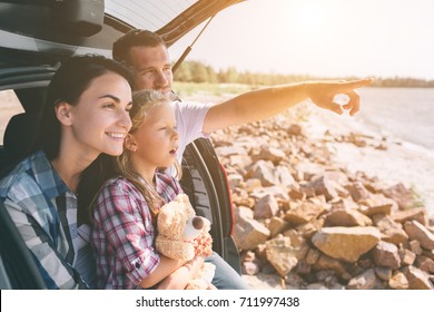 Happy family on a road trip in their car. Dad, mom and daughter are traveling by the sea or the ocean or the river. Summer ride by automobile - Shutterstock ID 711997438