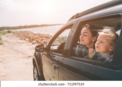 Happy Family On A Road Trip In Their Car. Dad, Mom And Daughter Are Traveling By The Sea Or The Ocean Or The River. Summer Ride By Automobile