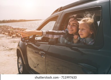 Happy Family On A Road Trip In Their Car. Dad, Mom And Daughter Are Traveling By The Sea Or The Ocean Or The River. Summer Ride By Automobile