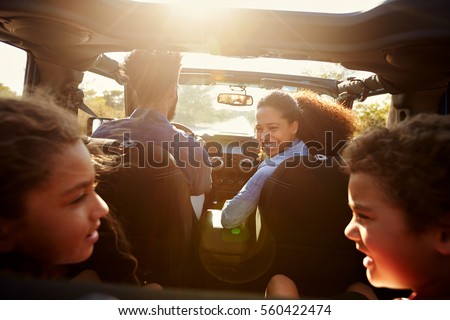 Happy family on a road trip in their car, rear passenger POV