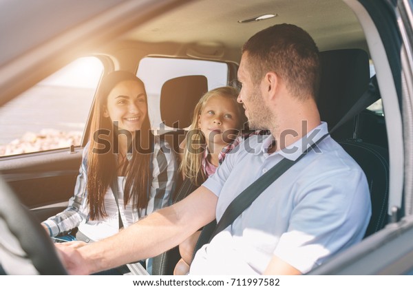Happy family on a road trip in their car. Dad,\
mom and daughter are traveling by the sea or the ocean or the\
river. Summer ride by\
automobile