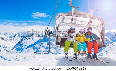 Happy family on ski lift chair enjoying winter ski vacations in mountains  Playing with snow and sun in high mountains. Winter holidays.