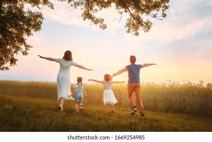 Happy Family On Summer Walk! Mother, Father And Daughters Walking In The Park And Enjoying The Beautiful Nature.