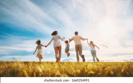 Happy family on summer walk! Mother, father and daughters walking in the Park and enjoying the beautiful nature.                               