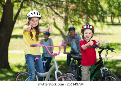 Happy family on their bike at the park with thumbs up on a sunny day