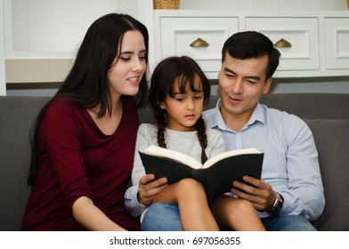 The happy of the family on vacation at home. Parent are teaching daughter read a book.
