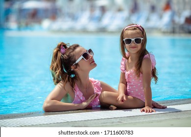 Happy Family On Vacation. Mother And Daughter In Sunglasses In Pink Swimsuits Have Fun In The Summer By The Pool.