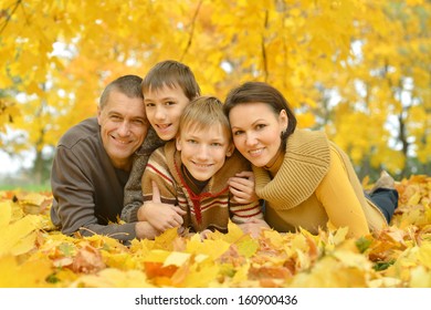 Happy Family On A Walk During The Fall Of The Leaves In The Park