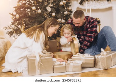 Happy family opening christmas gifts near a decorated christmas tree, enjoying festive moments together - Powered by Shutterstock