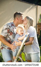Happy family outdoor. mom, son and dad on the back yard. happy parenting concept. family splash on each other water from the hose. maternity leave. toddler boy. blond family. young family photo shoot. - Shutterstock ID 1496473148