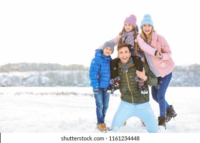 Happy Family Outdoors During Snowfall. Winter Vacation. Space For Text