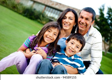 Happy family outdoors with a house at the background