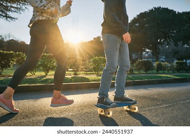 Happy family outdoors, mother and son go in sports, Boy rides skateboard, mom runs on sunny day. Silhouette people at sunset. Health care, authenticity, sense of balance and calmness.