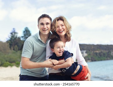 Happy Family Outdoors On A Beach Smiling