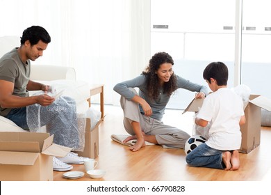 Happy family packing dishes together in their living-room for their removal