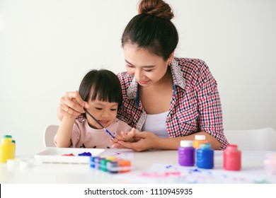 A Happy Family Is Painting. Mom Help Her Daughter Drawing