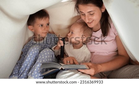 Mother reading book to her sons in the bed