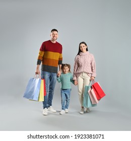 Happy Family With Paper Bags On Grey Background. Christmas Shopping