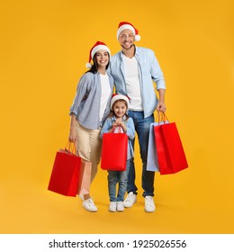 Happy Family With Paper Bags On Yellow Background. Christmas Shopping