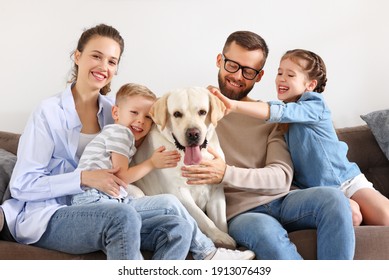 Happy Family: Parent With Cheerful Kids Playing With Their Favorite Pet Dog Labrador At Home