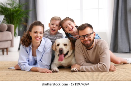 happy family: parents with cheerful kids hugging and playing with their favorite pet dog labrador at home